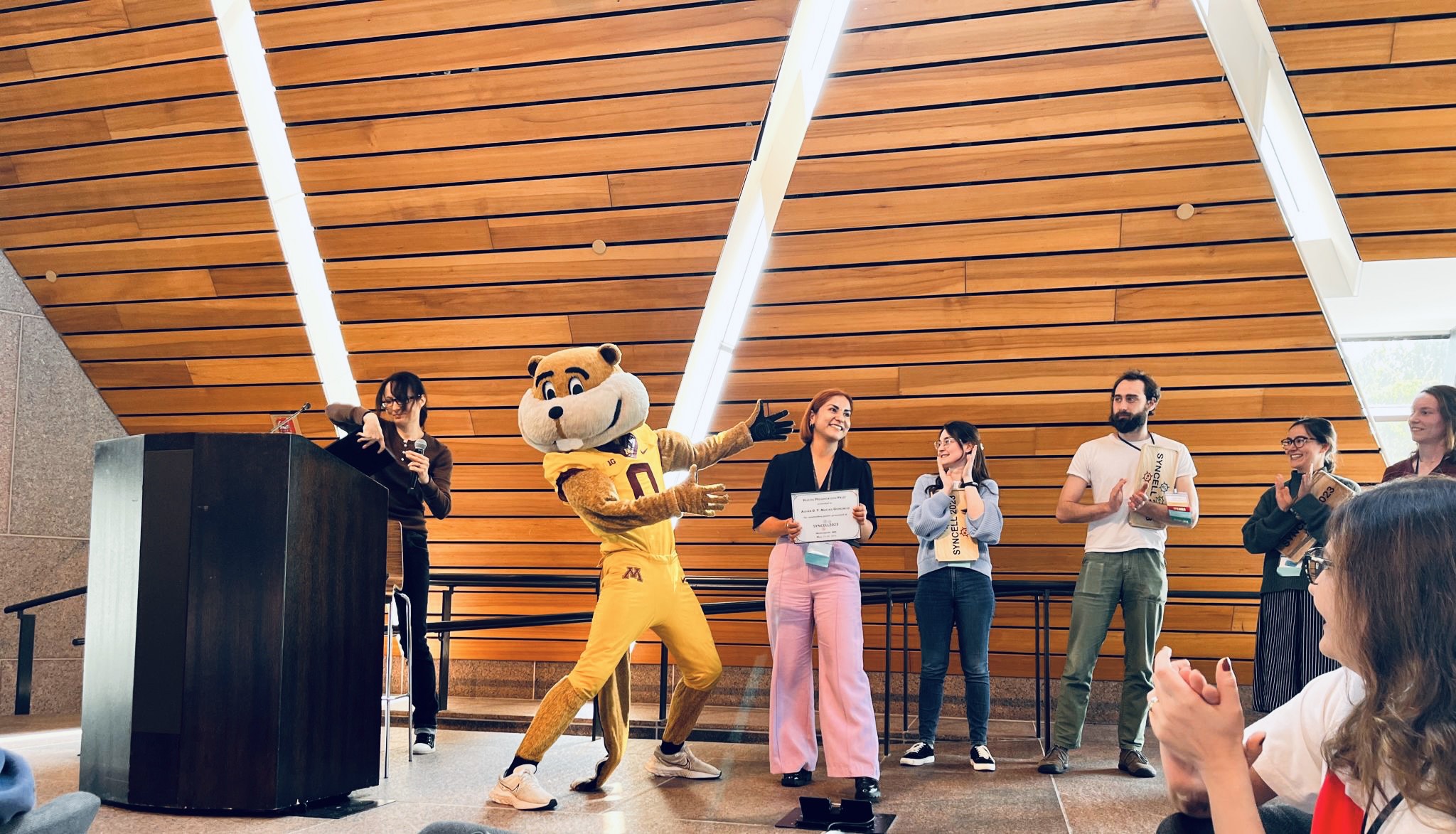 photo: Gonzalez accepts her prize from conference chair Kate Adamala and University of Minnesota mascot Goldy Gopher. 